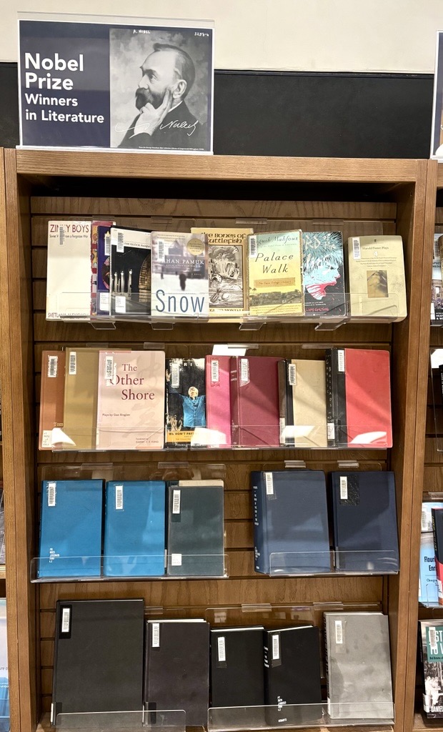 A book display featuring books with a variety of colours and images. A sign reading Nobel Prize Winners sits on top with the image of a bearded man in his 40s.