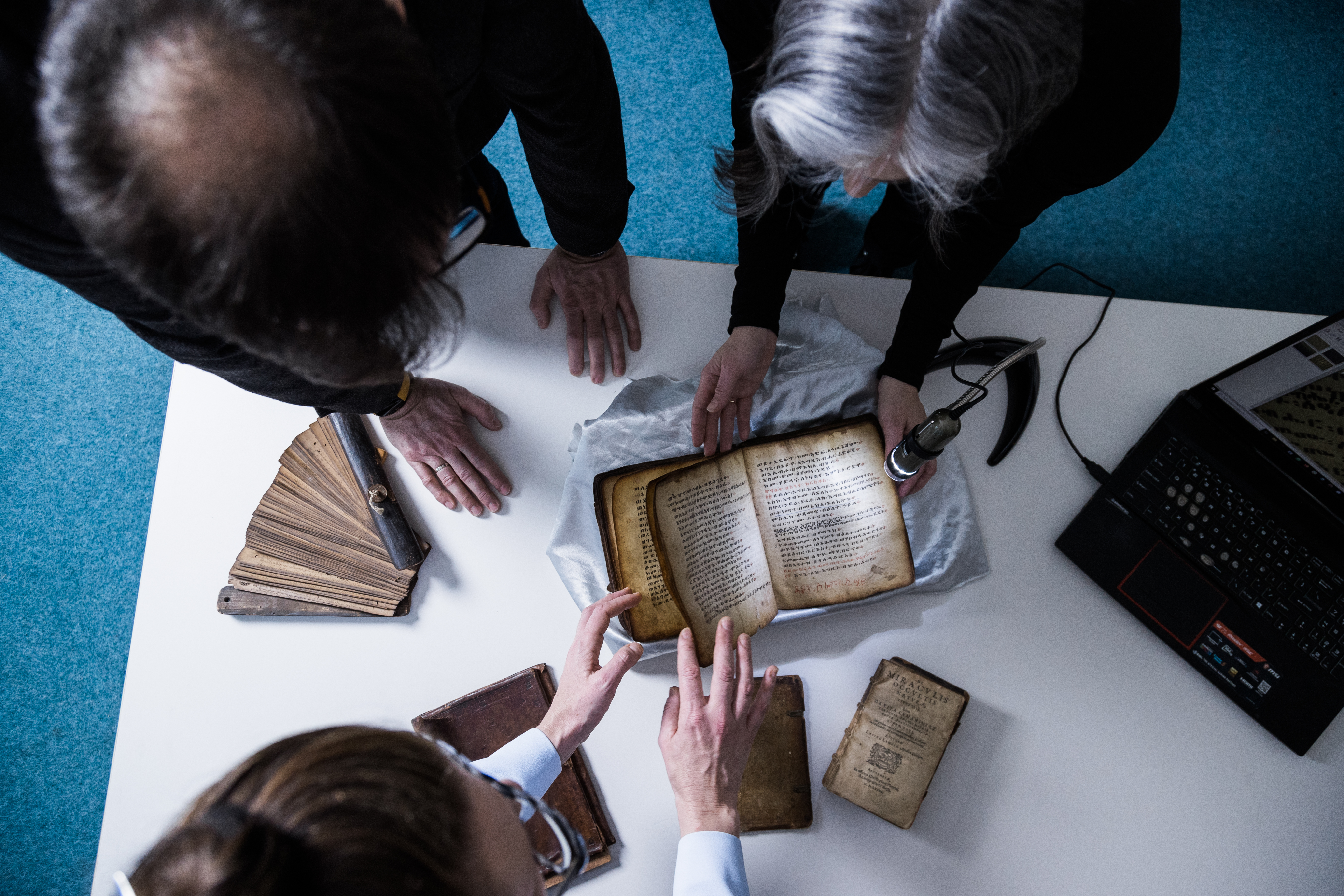 Researchers at the Old Book, New Science Lab lean over a book at the Thomas Fisher Library