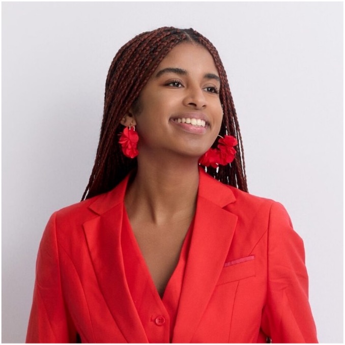 Shoulder and up image of Hannah Permaul Flores,a woman in a red blazer and shirt with red earrings, smiling