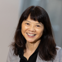 headshot of Darlene Chow, an east asian woman with dark hair and bangs in a grey blazer and black shirt. 