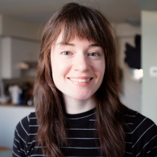 Headshot of Emily Woehrle. She has brown hair and bangs and is wearing a black and white striped shirt.