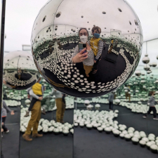 photo of woman holding a child inside Yayoi Kusama&#039;s Infinity Mirrored Room exhibit.