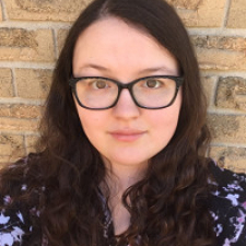 Eden&#039;s face: she wears black glasses and has wavy dark brown hair